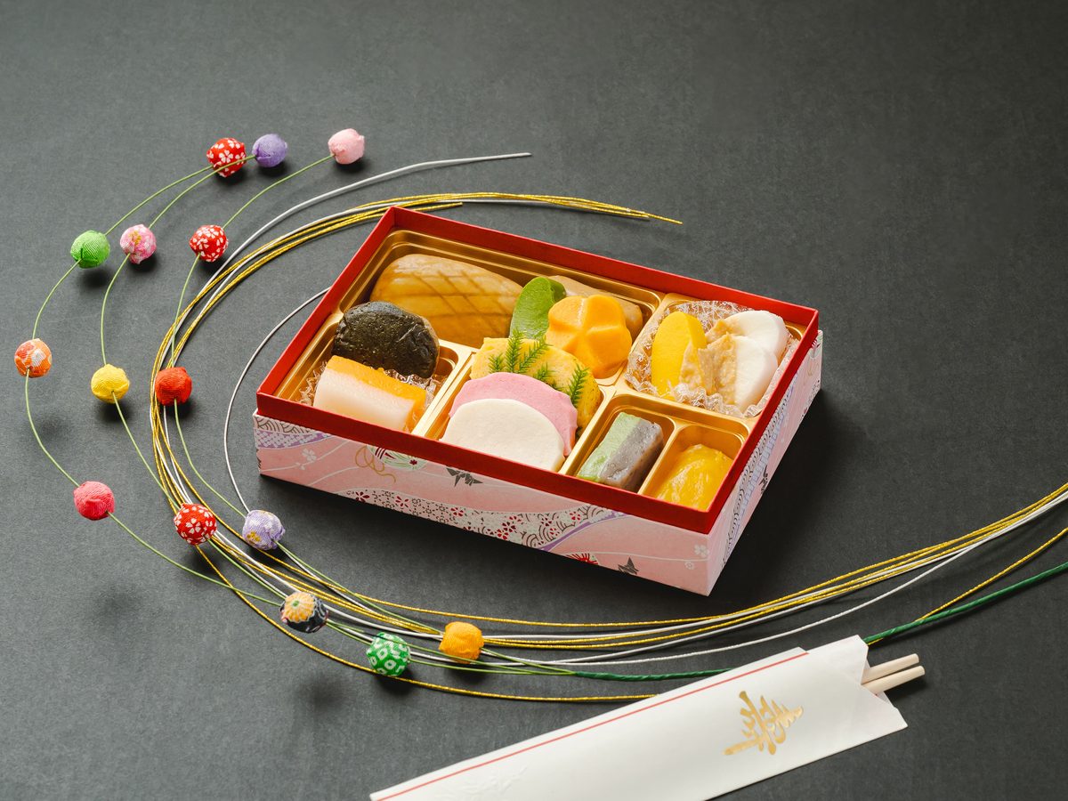 やわらかおせち重（まろやか）の盛り付け写真。赤い重箱に六つの仕切りで料理が並ぶ